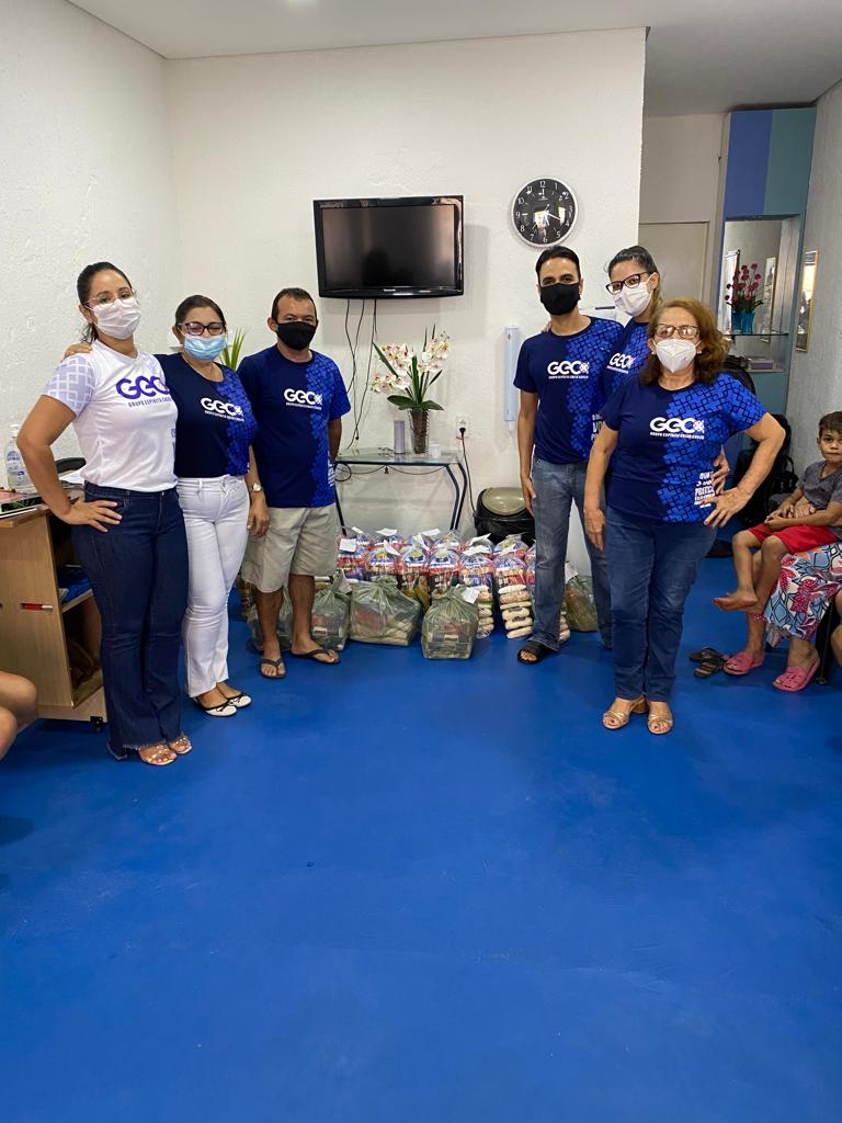 Equipe de voluntários do GECX reunida com cestas básicas para doação